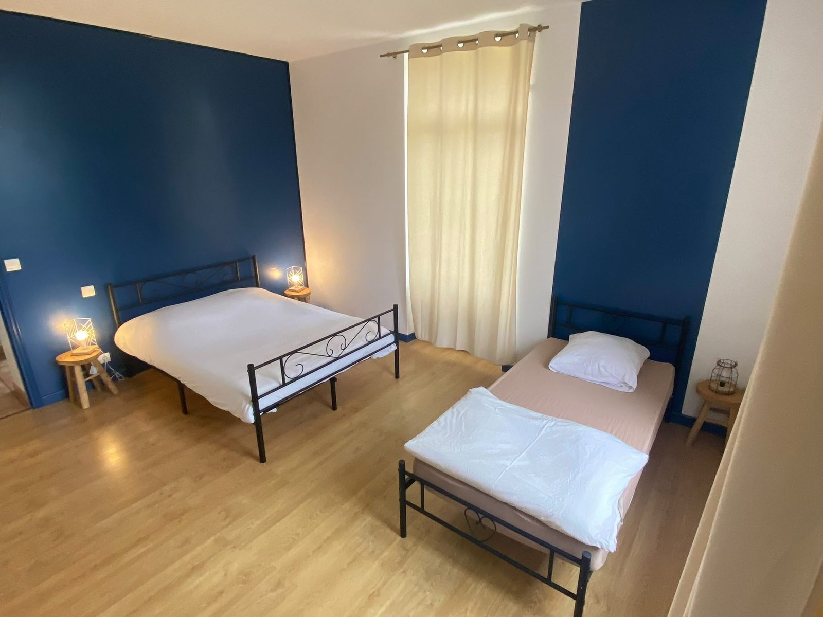 Chambre au mur bleu nuit avec un lit double et un lit simple