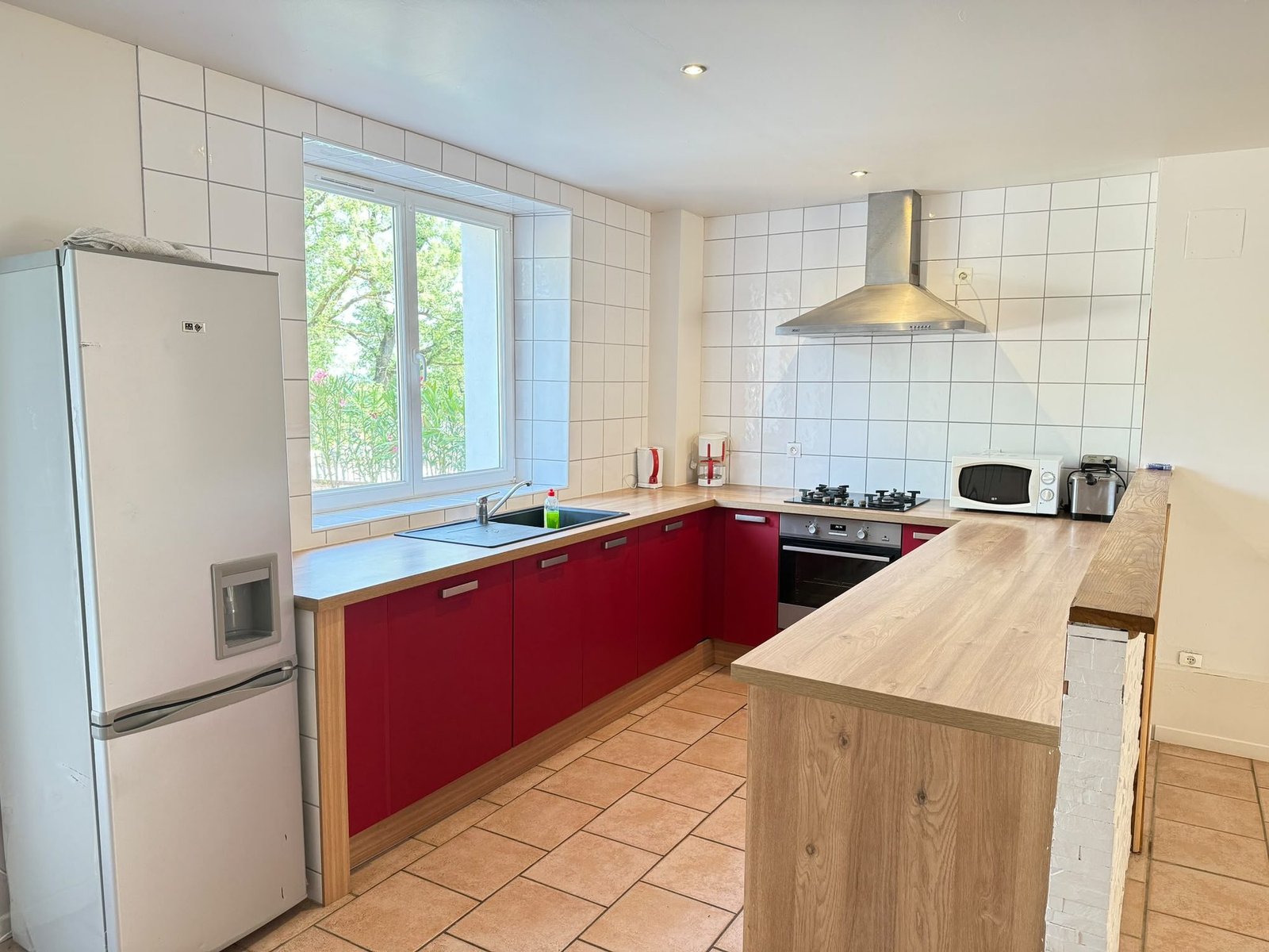Cuisine équipée aux façades rouges et plan de travail en bois