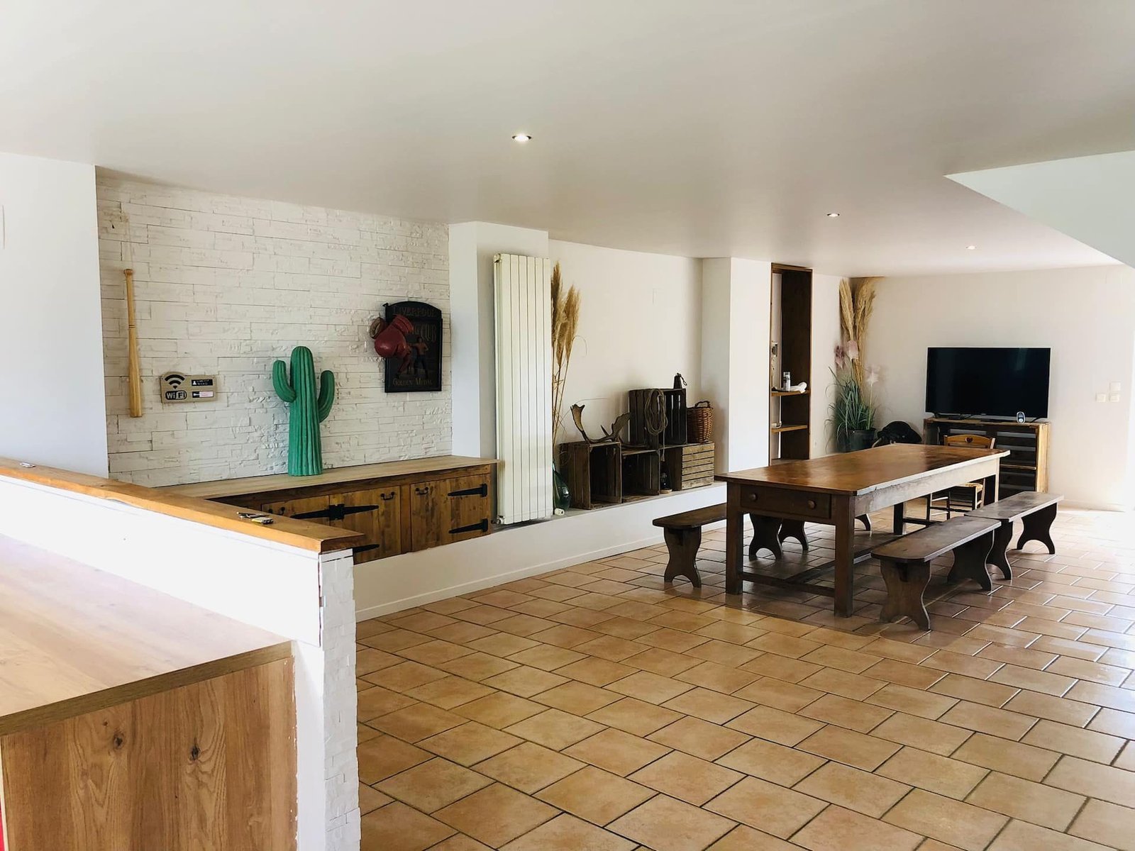 Grande table en bois massif, bancs et coin salon dans la pièce de vie
